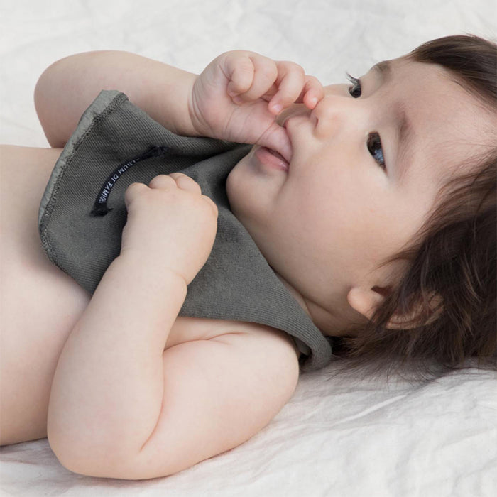 Baby laying down wearing a grey jersey bib.