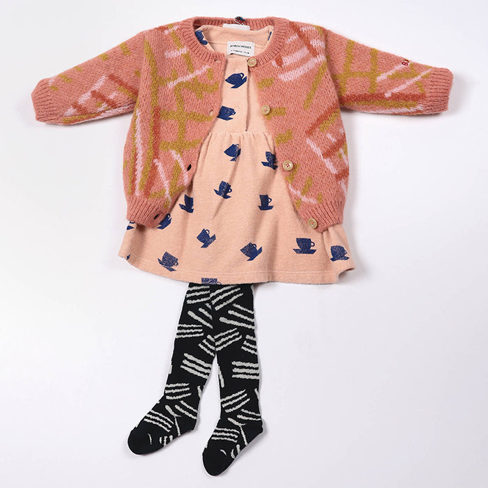 Baby outfit with a pink dress and cardigan with black tights with a white knitted lines pattern.