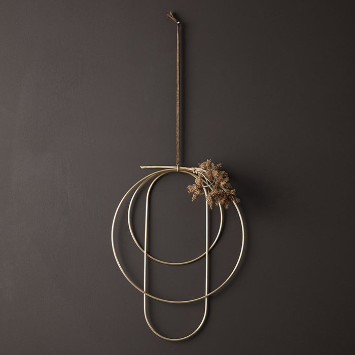 Gold coloured brass rings in three shapes and sizes with some dried flowers.