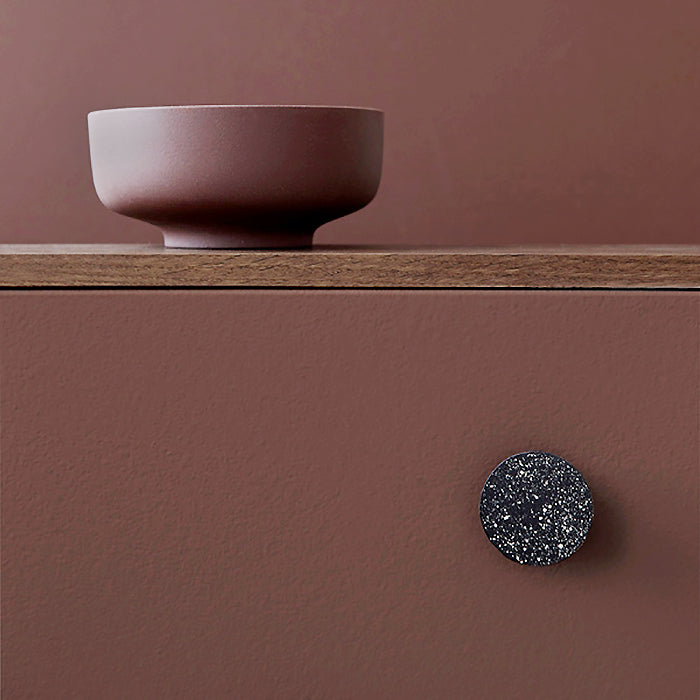 Wall hook in black with white speckles on a wall.