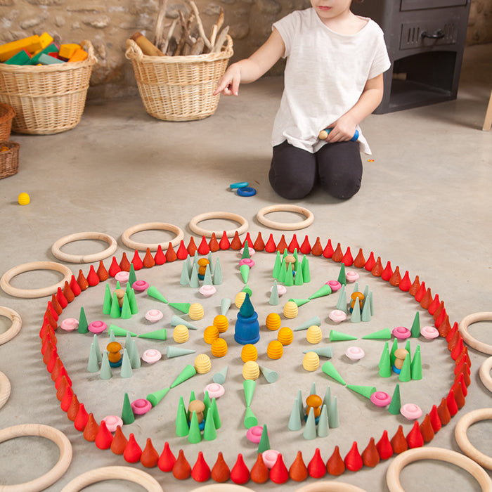 Child playing with mini wooden pieces in various shapes and colours.