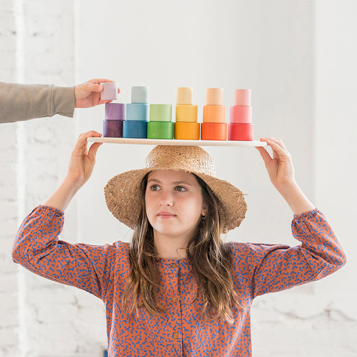 Girl holding nesting bowls in rainbow colours.
