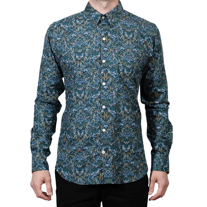 Man wearing a long sleeved button up shirt in a blue and green floral print.