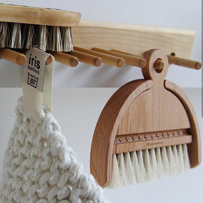 Wooden rack with a brush and kettle holder hanging.