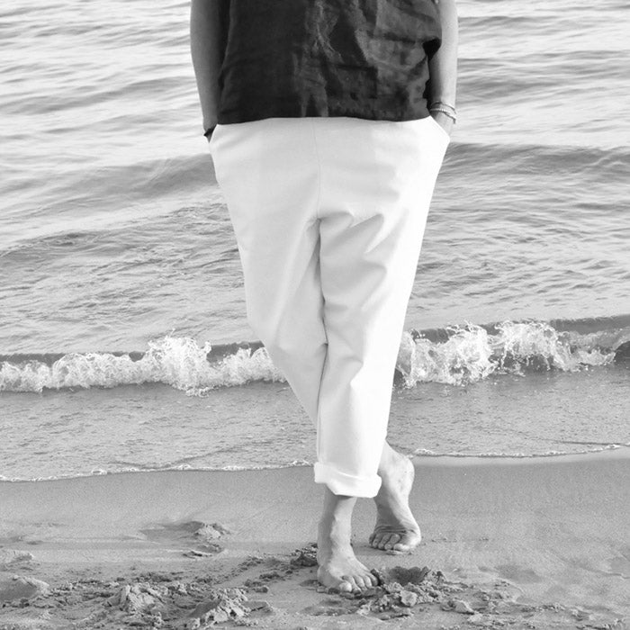 Woman standing on a beach wearing white loose fit jeans.