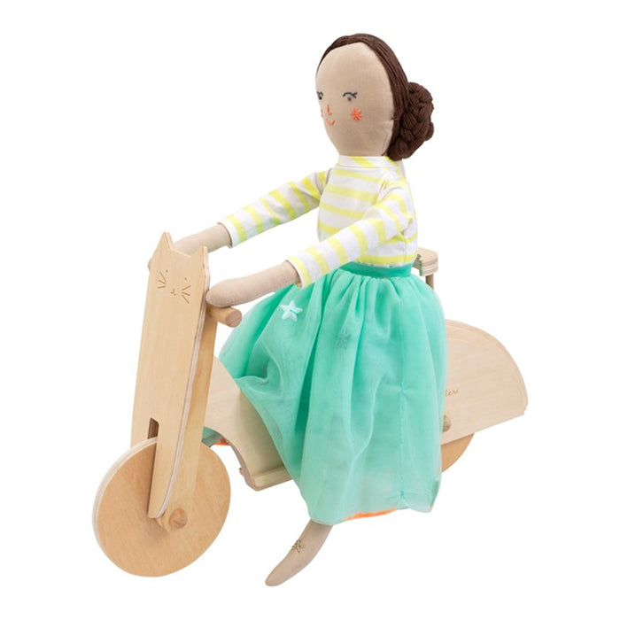 Doll sitting on a wooden moped.