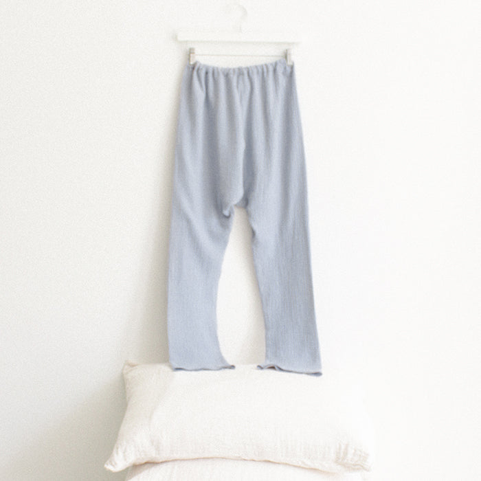 Light blue muslin pants from the back hanging above a stack of pillows.