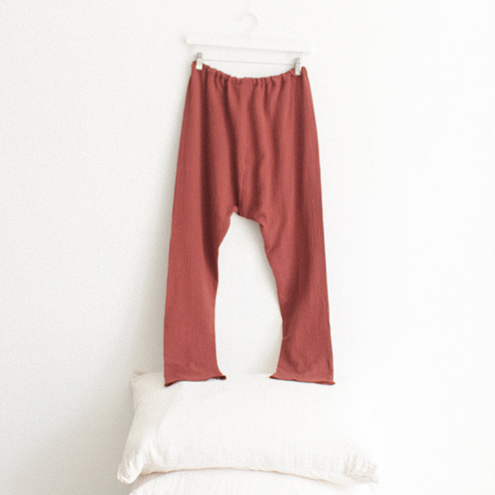 Red brown muslin pants from the back hanging above a stack of pillows.