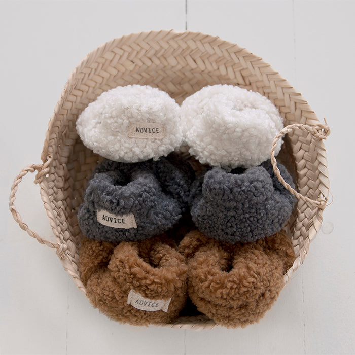 Basket holding three colours of faux shearling baby booties.