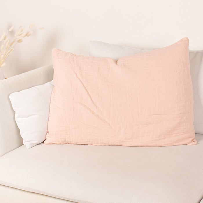 Pink textured cotton pillow on a couch.