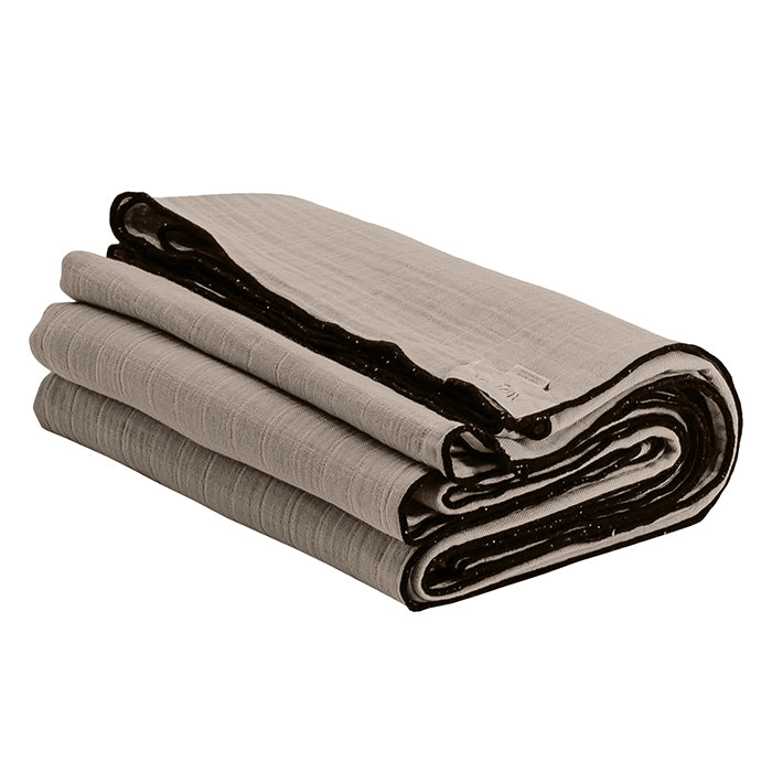 Beige folded cotton gauze tablecloth with black sewn edges.