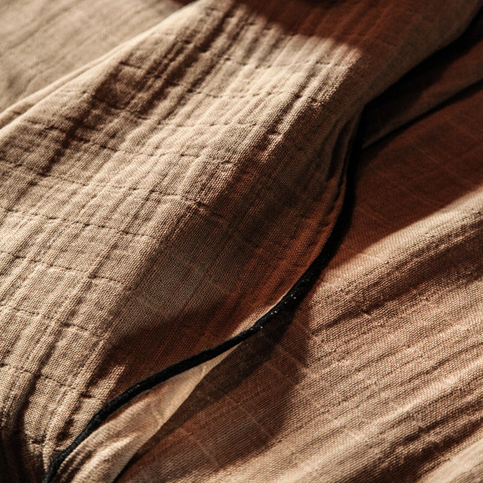 Close up of the beige cotton gauze tablecloth with black sewn edges.