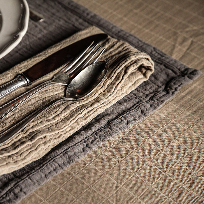 Beige cotton gauze tablecloth with a place setting.