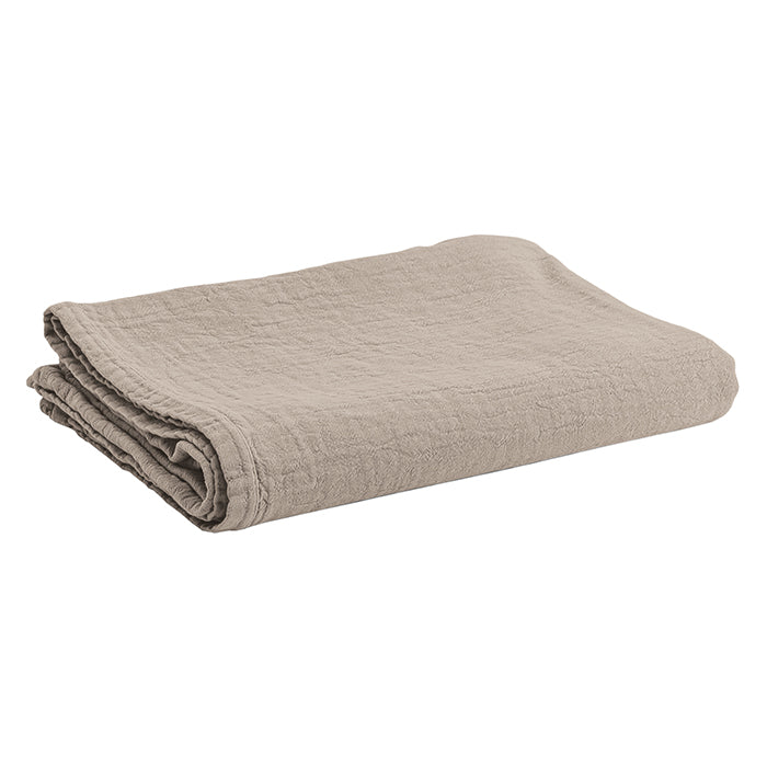 Beige folded textured cotton tablecloth.