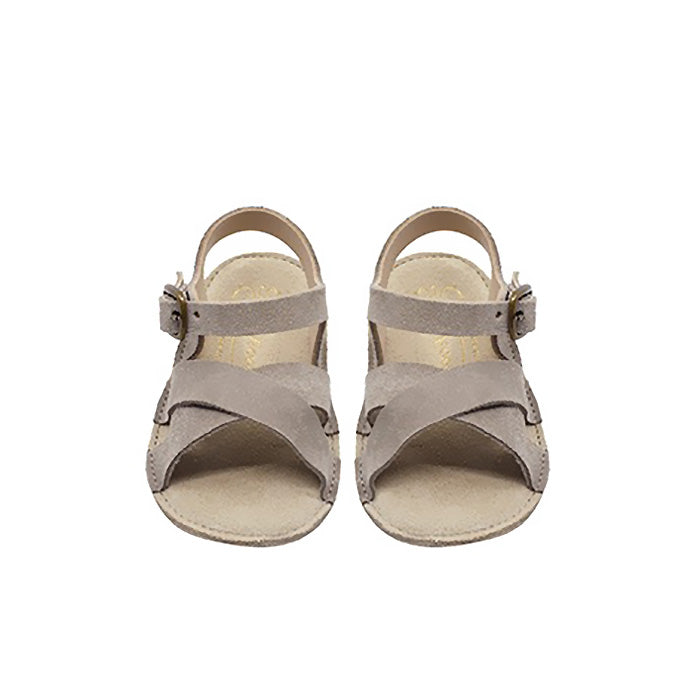 A pair of grey brown sandals with a buckle around the ankle from the front.