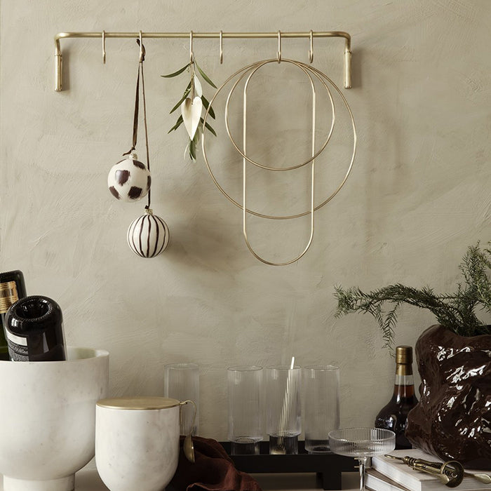 Gold coloured brass rings in three shapes and sizes hanging from hooks with holiday party decor.