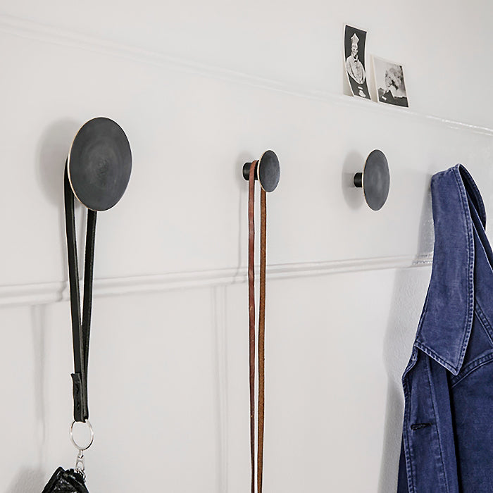 Round black wall hooks in various sizes on a wall.