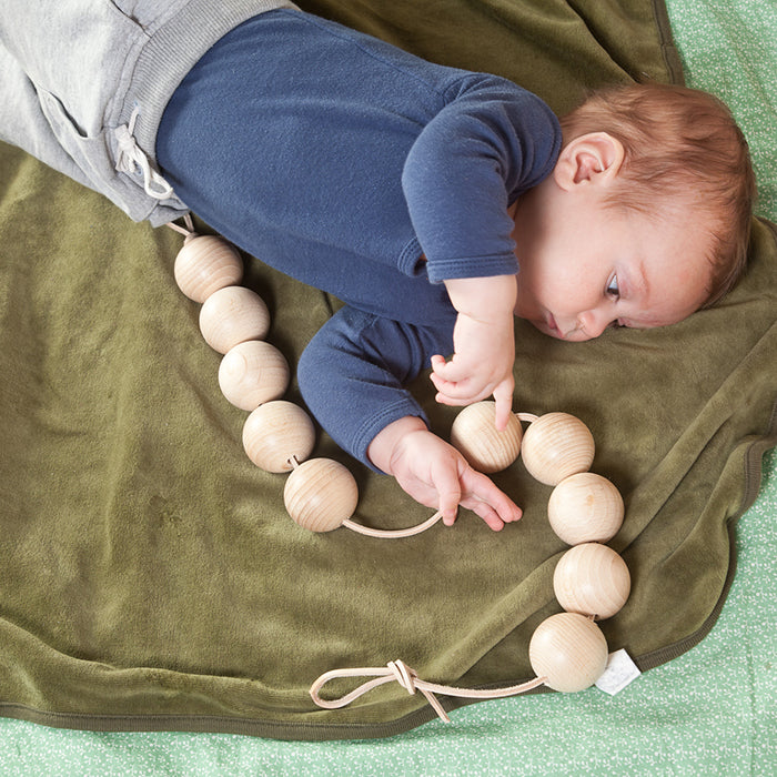Baby playing with a string of round wooden beads.