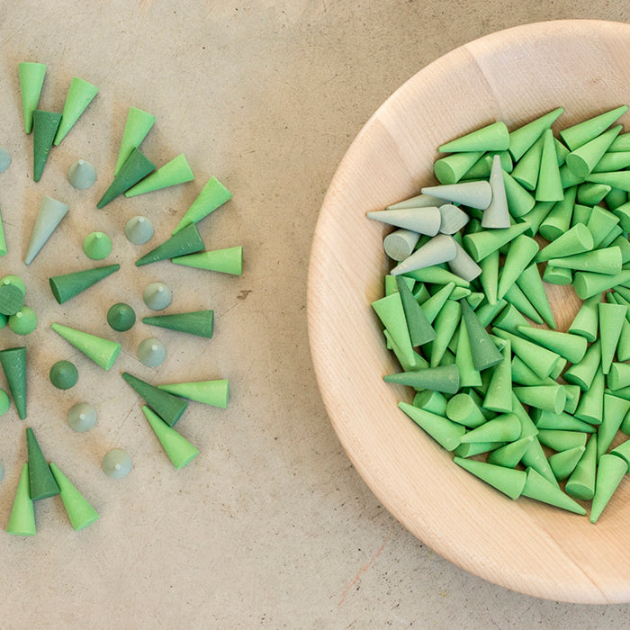 Wooden mini cone shaped pieces in various shades of green in a wooden bowl.