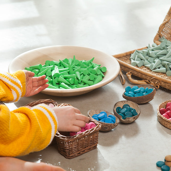 Child playing with mini wooden cone shaped pieces.