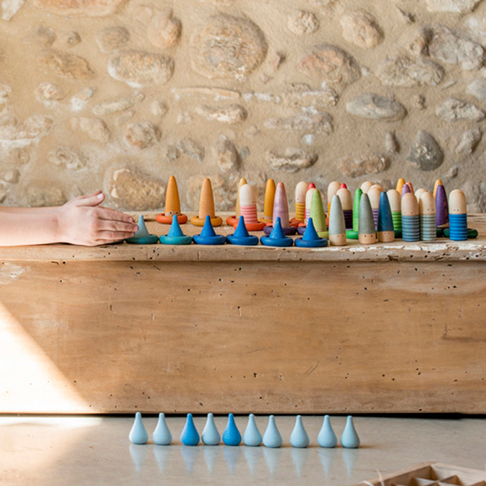 Child playing with mini wooden shaped pieces in various shades of blue.