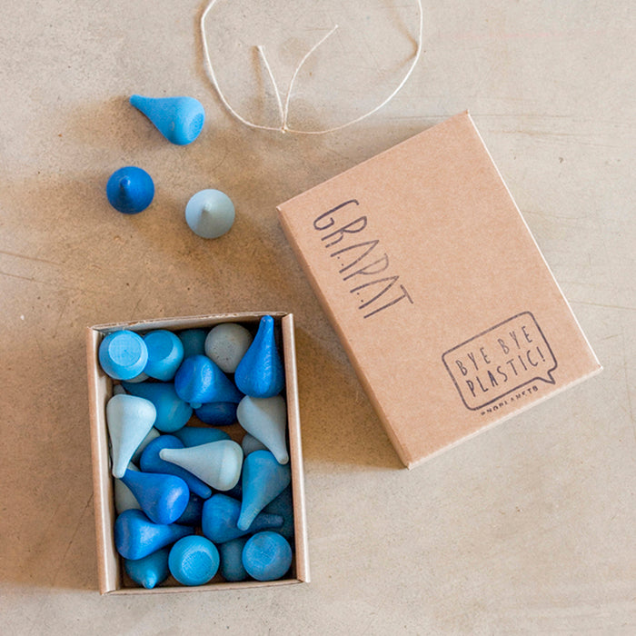 Wooden mini raindrop shaped pieces in various shades of blue in a box.