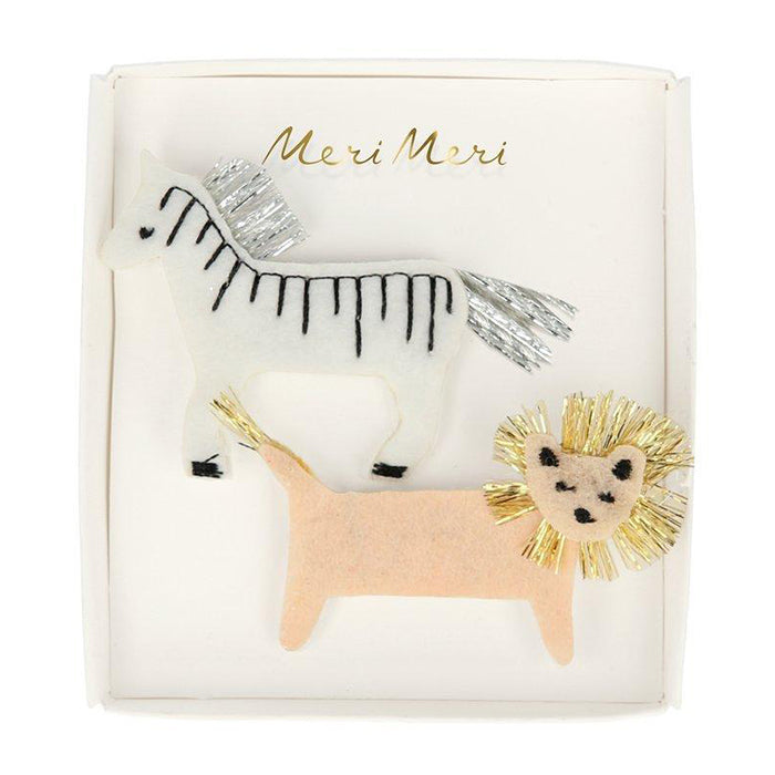 A box set of two felt hair clips with a lion and zebra design and embroidered details.