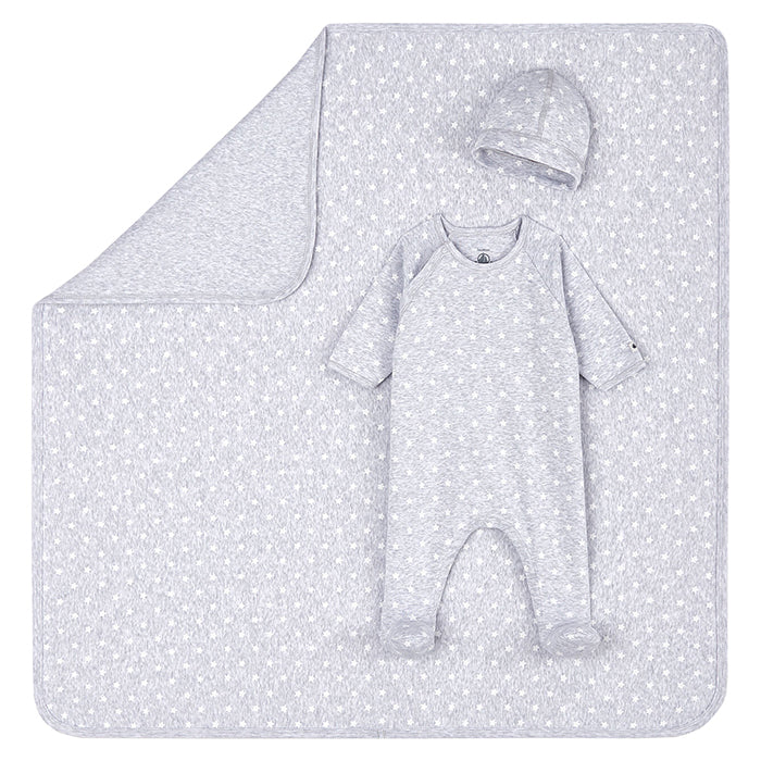 A baby gift set with clothing pieces laid on top of a blanket in grey with white star print.