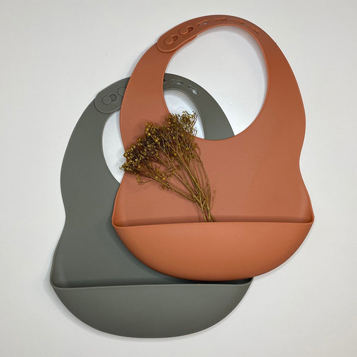 Two silicone baby bibs with pockets in brown and sage grey.
