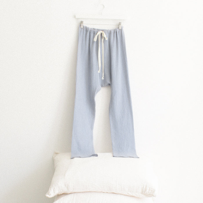 Light blue muslin pants hanging above a stack of pillows.