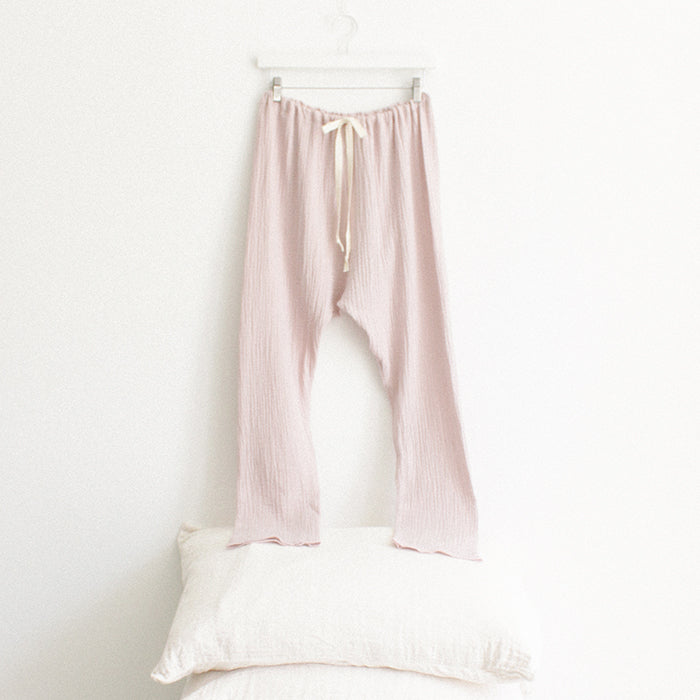 Light pink muslin pants hanging above a stack of pillows.