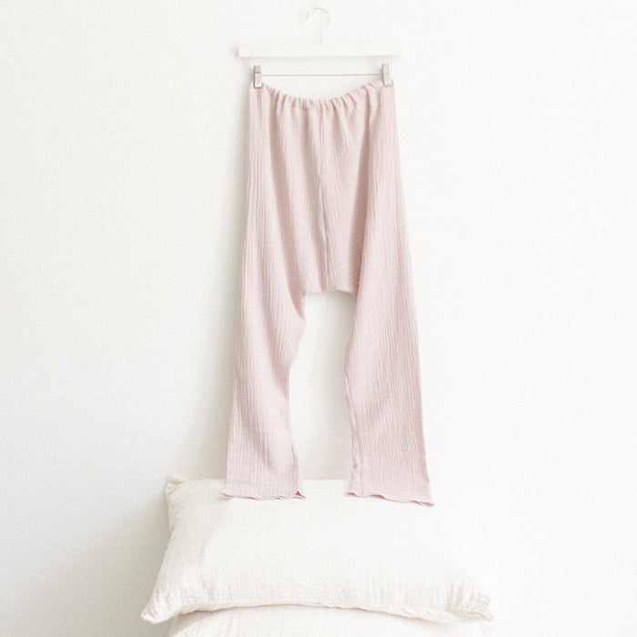 Light pink muslin pants from the back hanging above a stack of pillows.